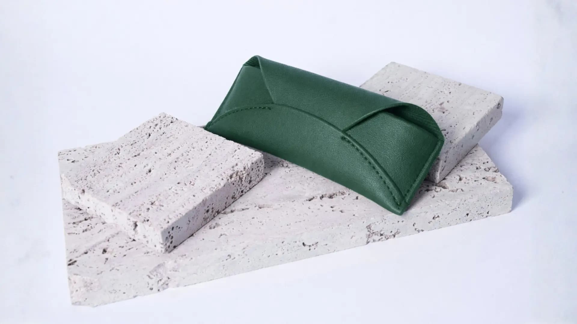 Luxury eyewear case resting on natural seashells and travertine stone, highlighting organic textures and premium finish